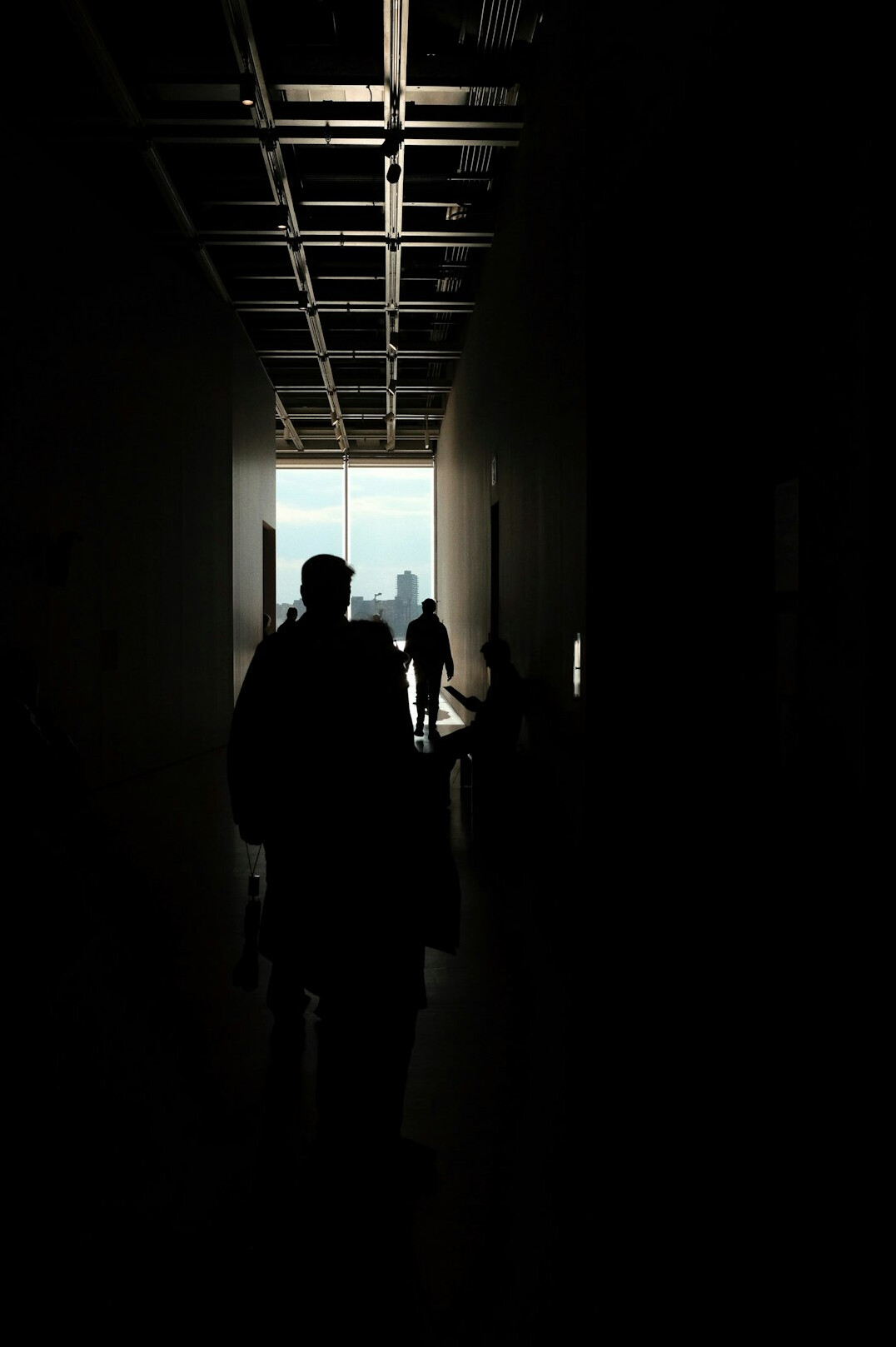 Distant anonymous silhouette walking through a museum hallway seen from behind